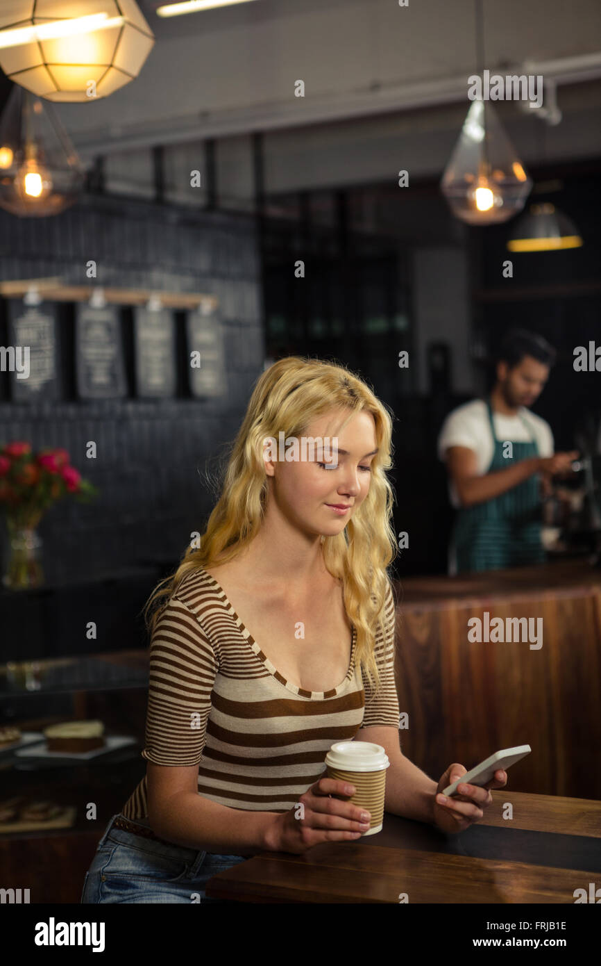 Femme buvant du café et using smartphone Banque D'Images