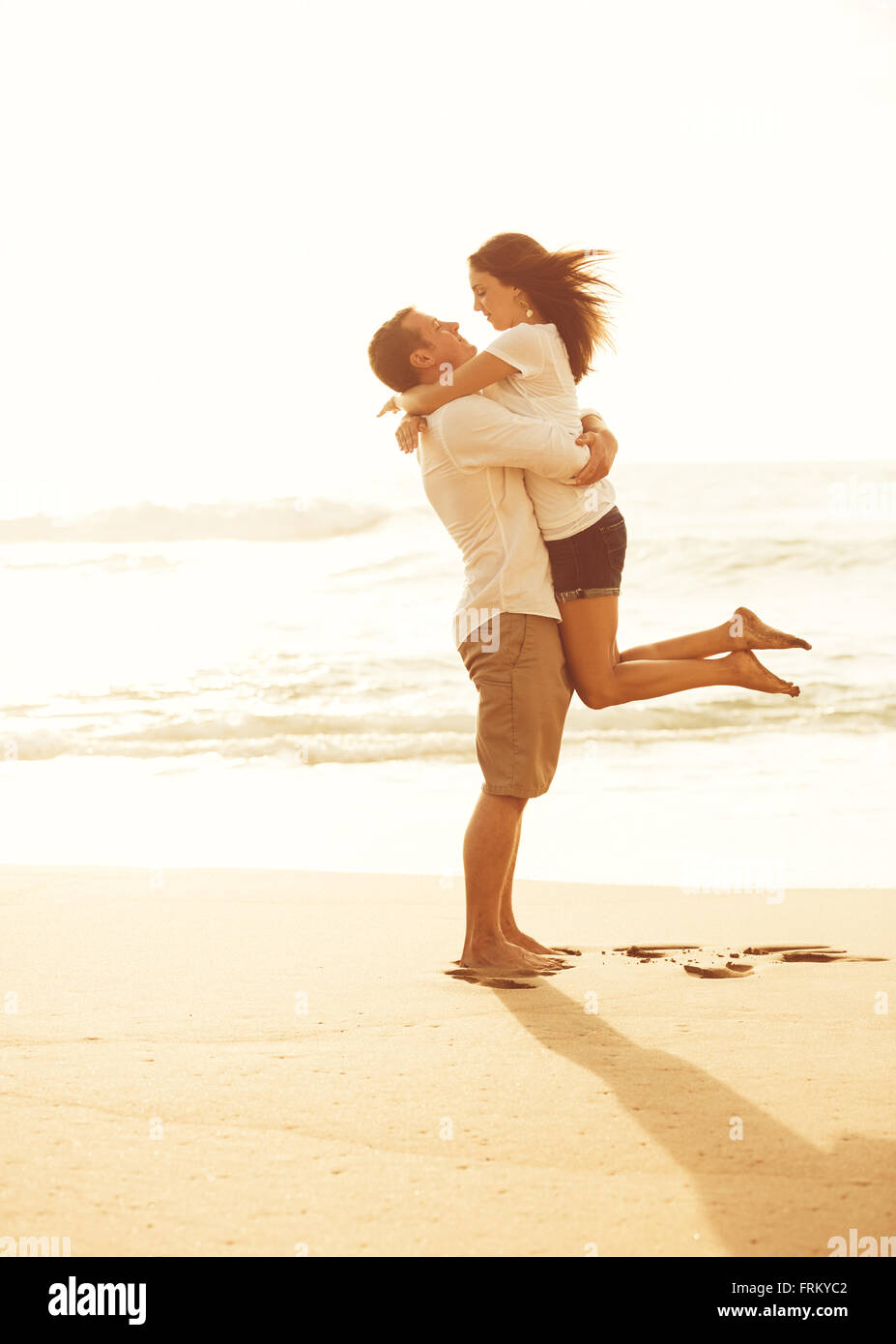 Heureux couple romantique sur la plage au coucher du soleil. Les jeunes amoureux en vacances. Banque D'Images