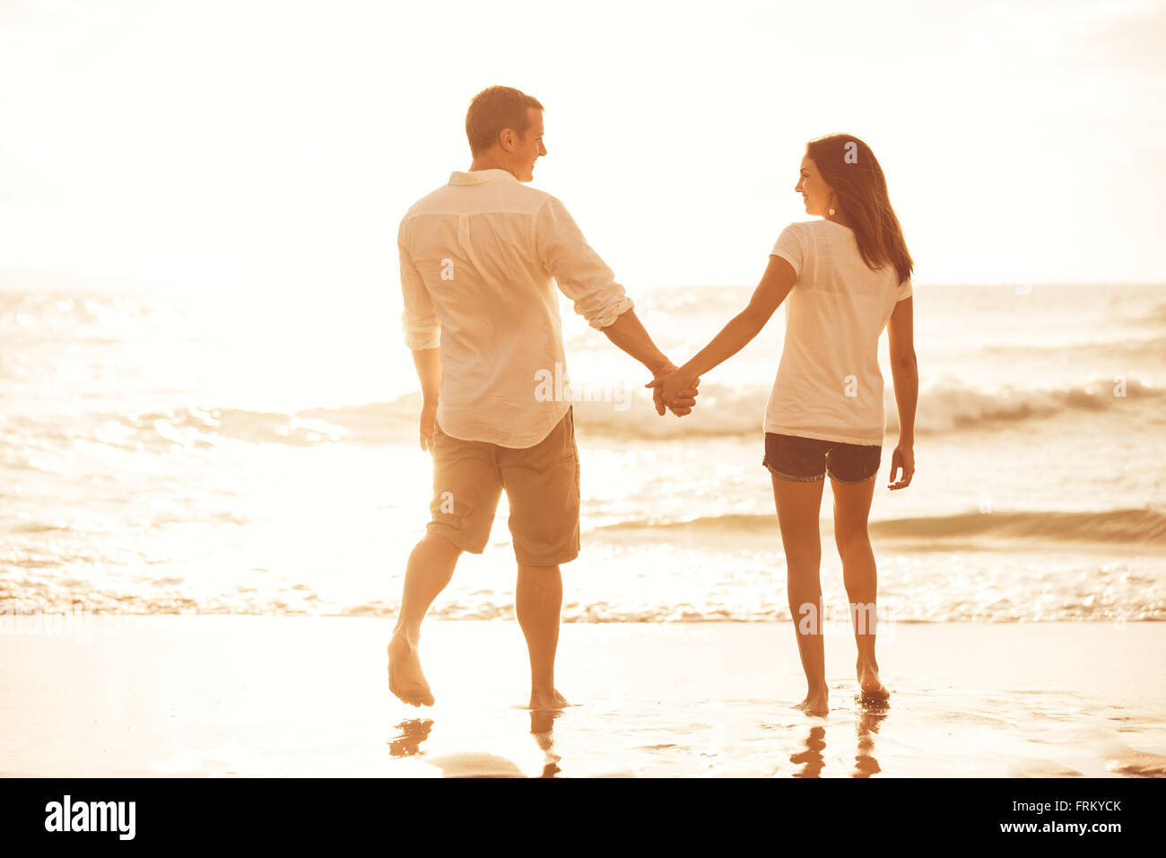 Heureux couple romantique sur la plage au coucher du soleil. Les jeunes amoureux en vacances. Banque D'Images