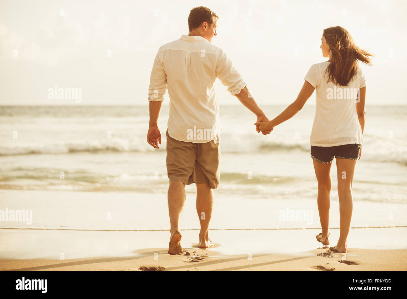 Heureux couple romantique sur la plage au coucher du soleil. Les jeunes amoureux en vacances. Banque D'Images