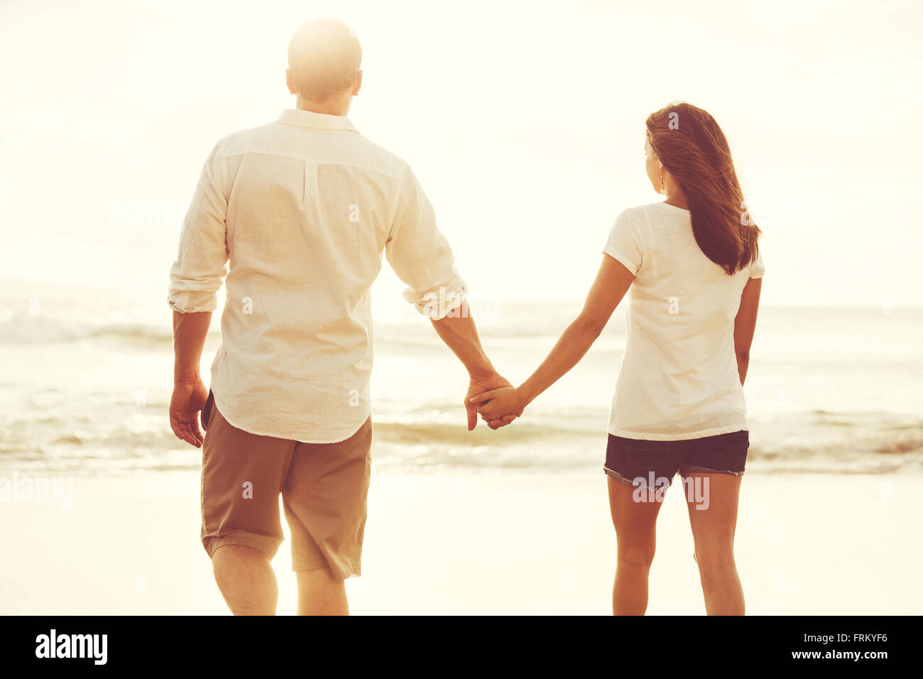 Heureux couple romantique sur la plage au coucher du soleil. Les jeunes amoureux en vacances. Banque D'Images