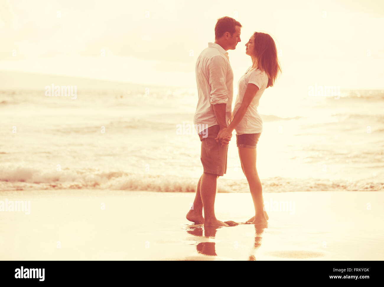 Heureux couple romantique sur la plage au coucher du soleil. Les jeunes amoureux en vacances. Banque D'Images