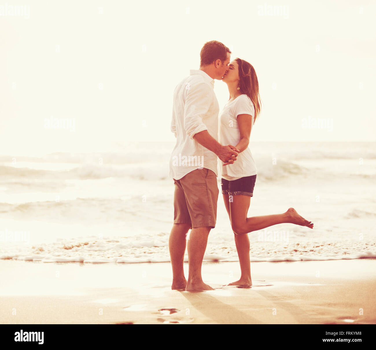 Heureux couple romantique sur la plage au coucher du soleil. Les jeunes amoureux en vacances. Banque D'Images