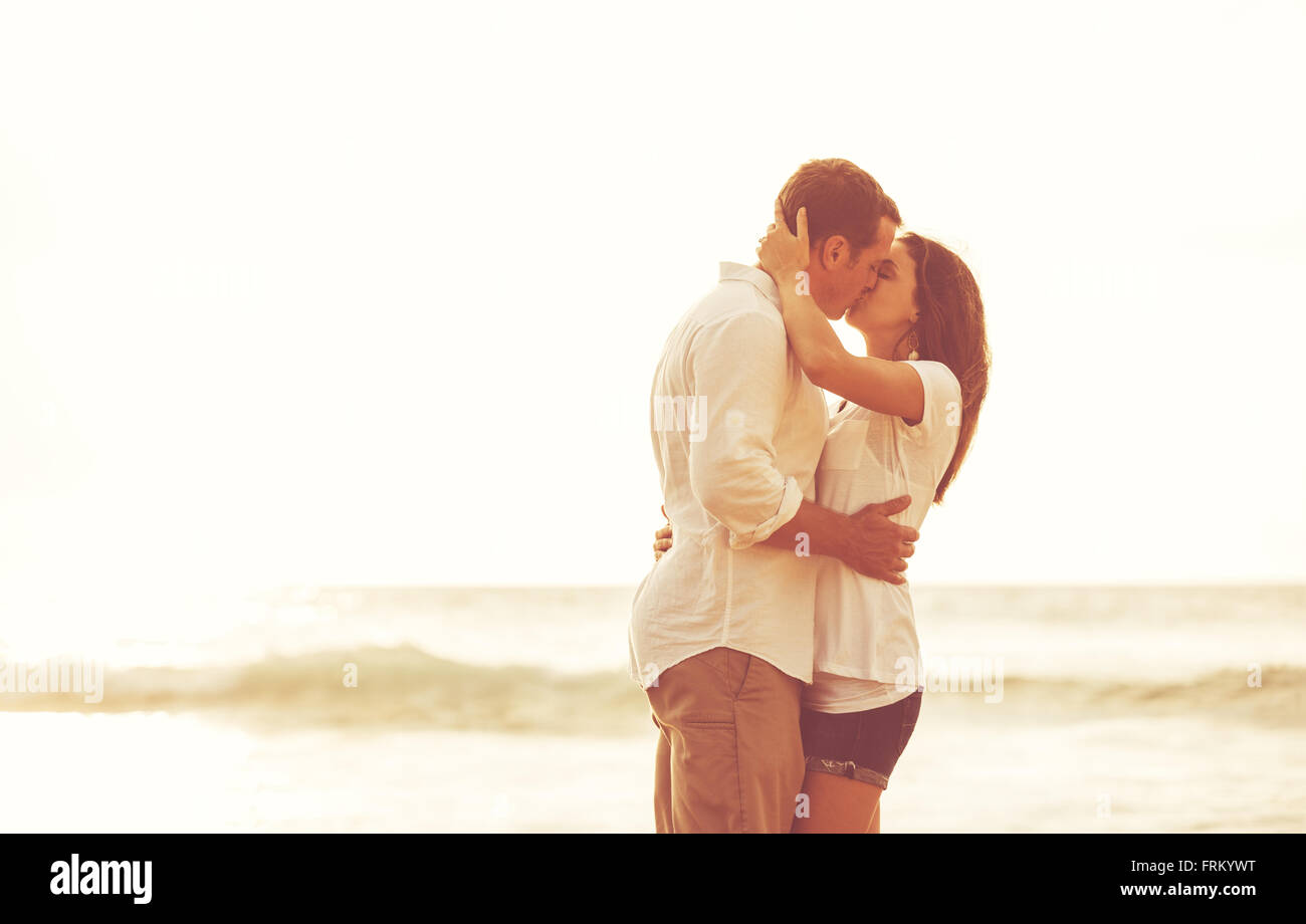 Heureux couple romantique sur la plage au coucher du soleil. Les jeunes amoureux en vacances. Banque D'Images