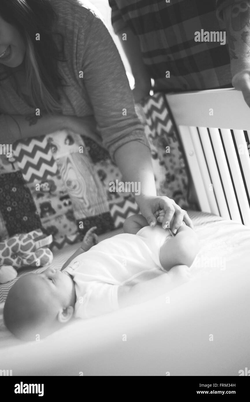 Nouvelle mère et père avec bébé garçon. Holding baby boys pieds et en le regardant dans le lit Banque D'Images