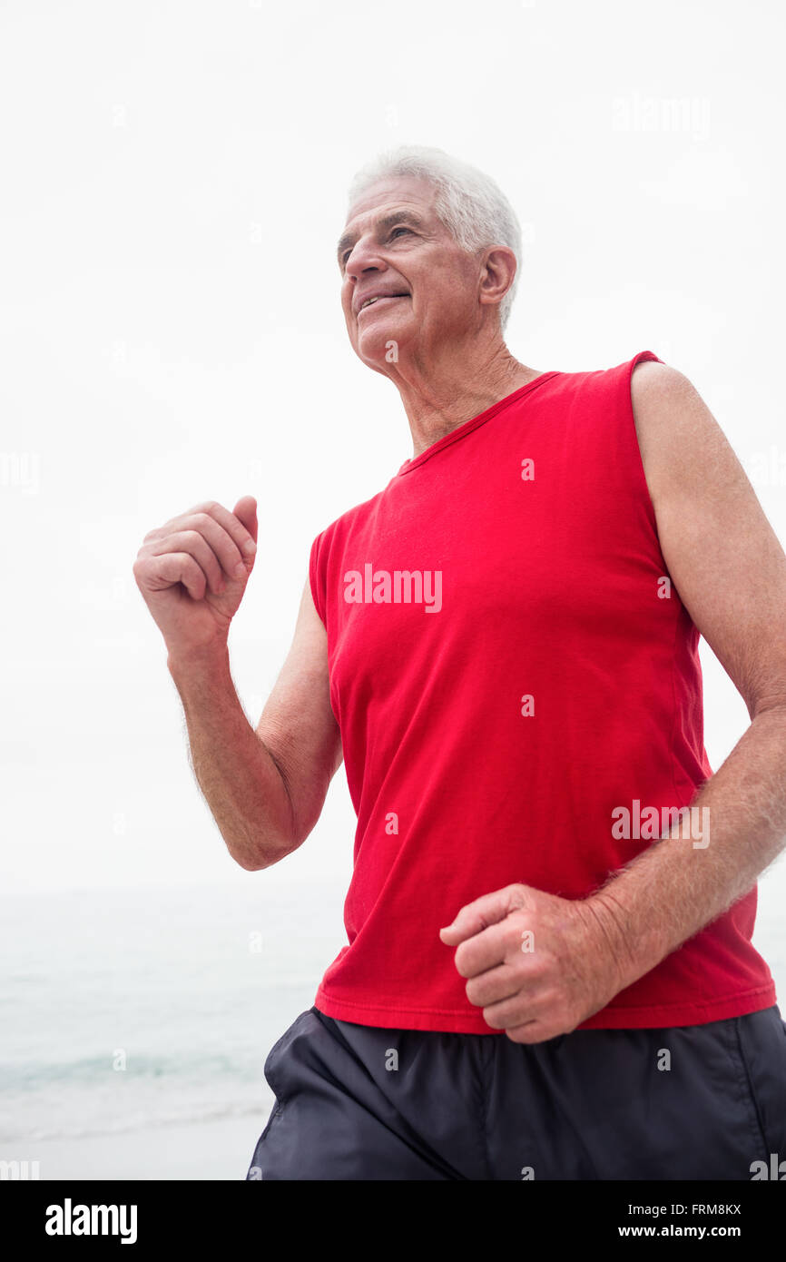 Senior man jogging sur la plage Banque D'Images