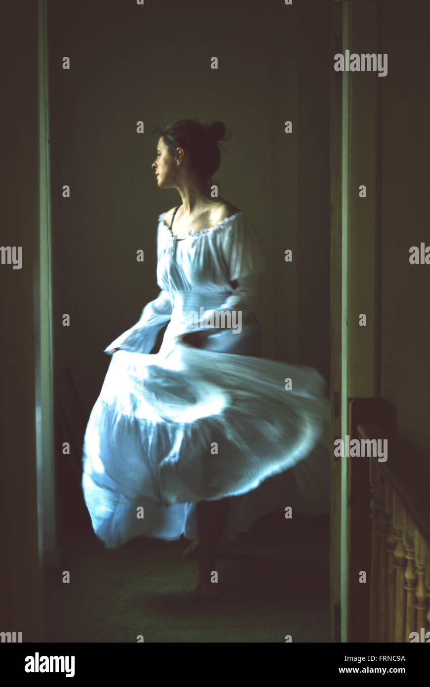 Jeune femme dansant dans une vieille maison longue robe romantique blanc Banque D'Images