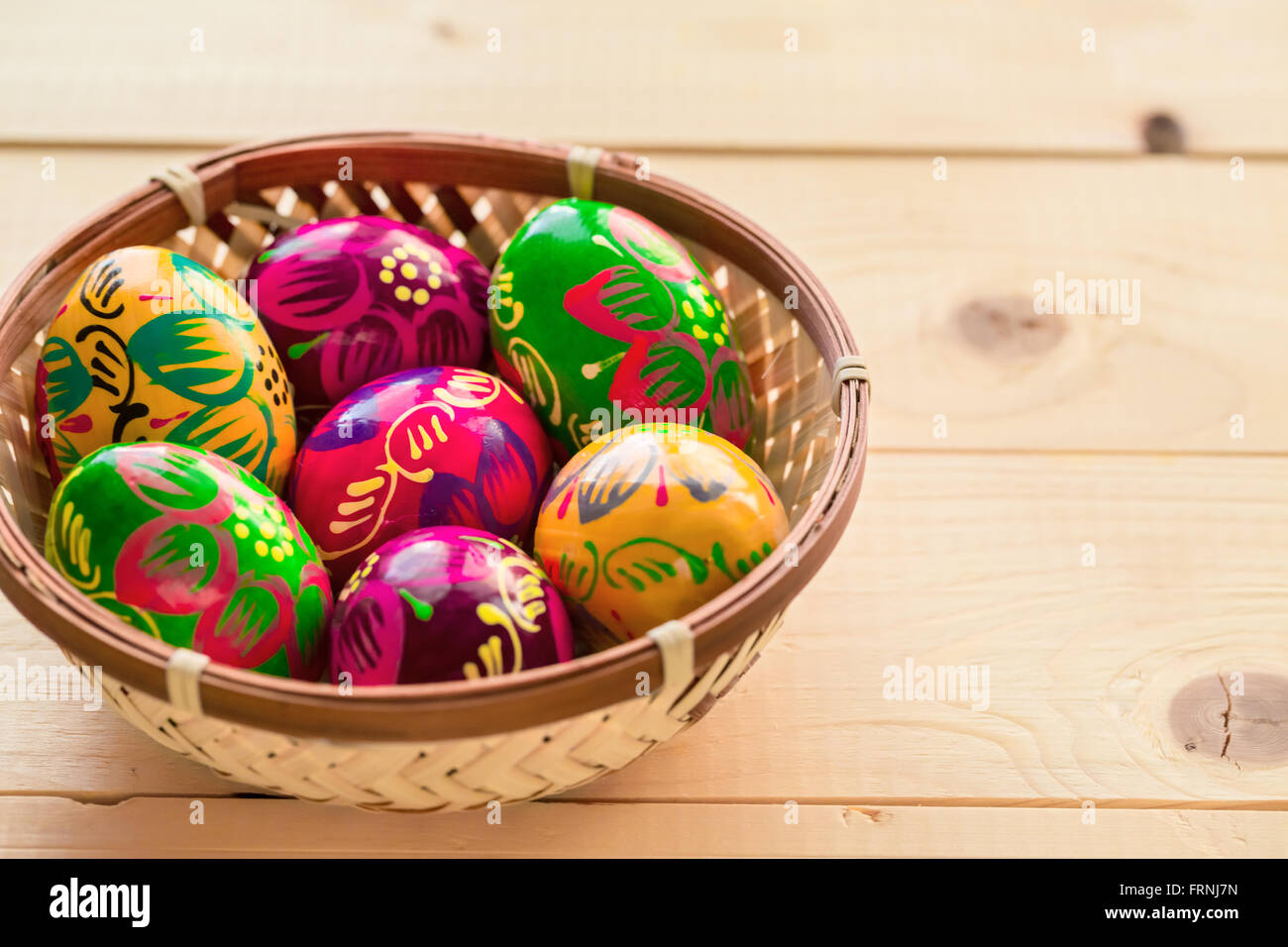 Belle a peint les oeufs de Pâques colorés dans un nid en osier sur un fond de bois Banque D'Images