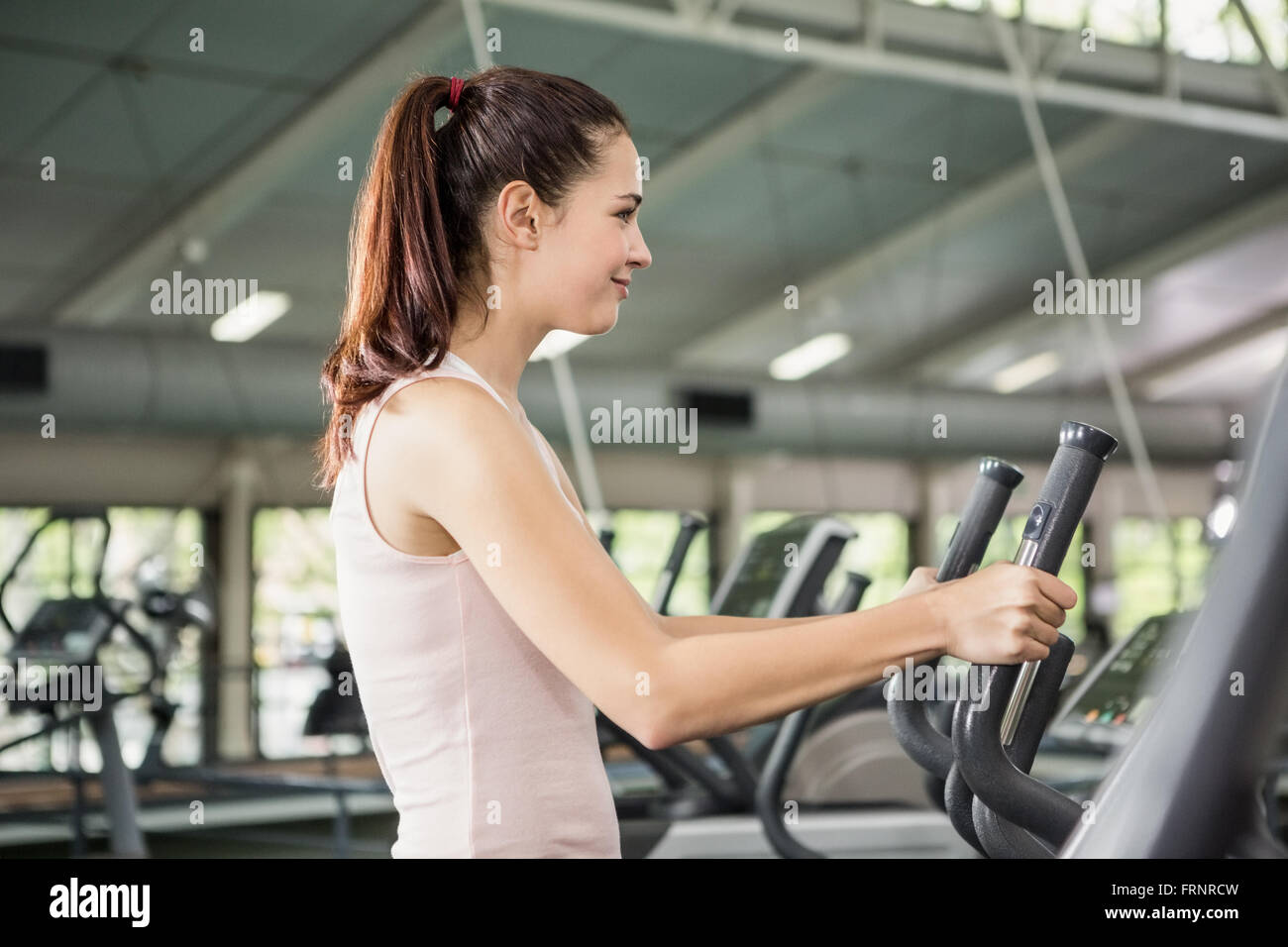 Belle femme exerçant sur la machine elliptique Banque D'Images