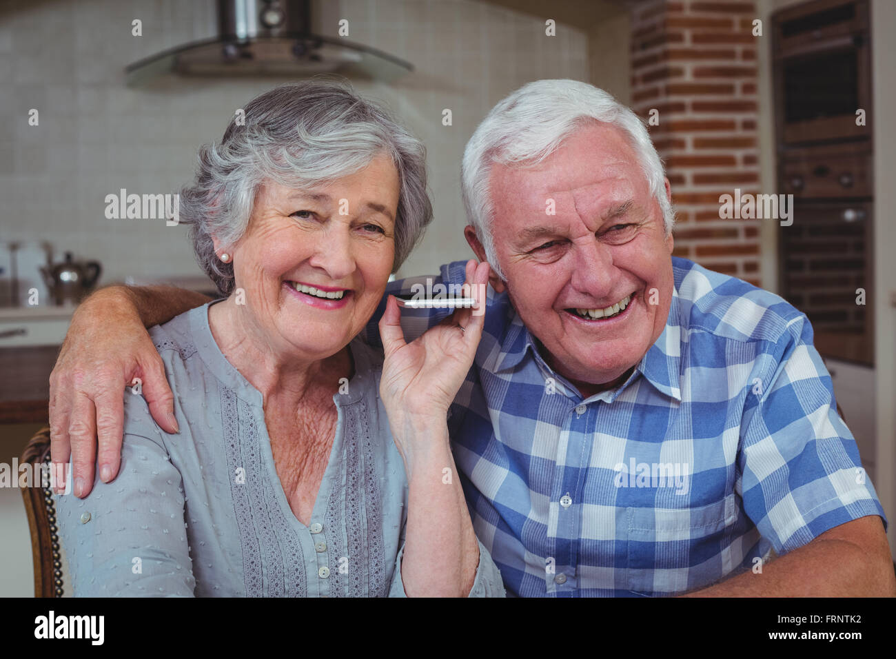 Senior couple listening music in kitchen Banque D'Images