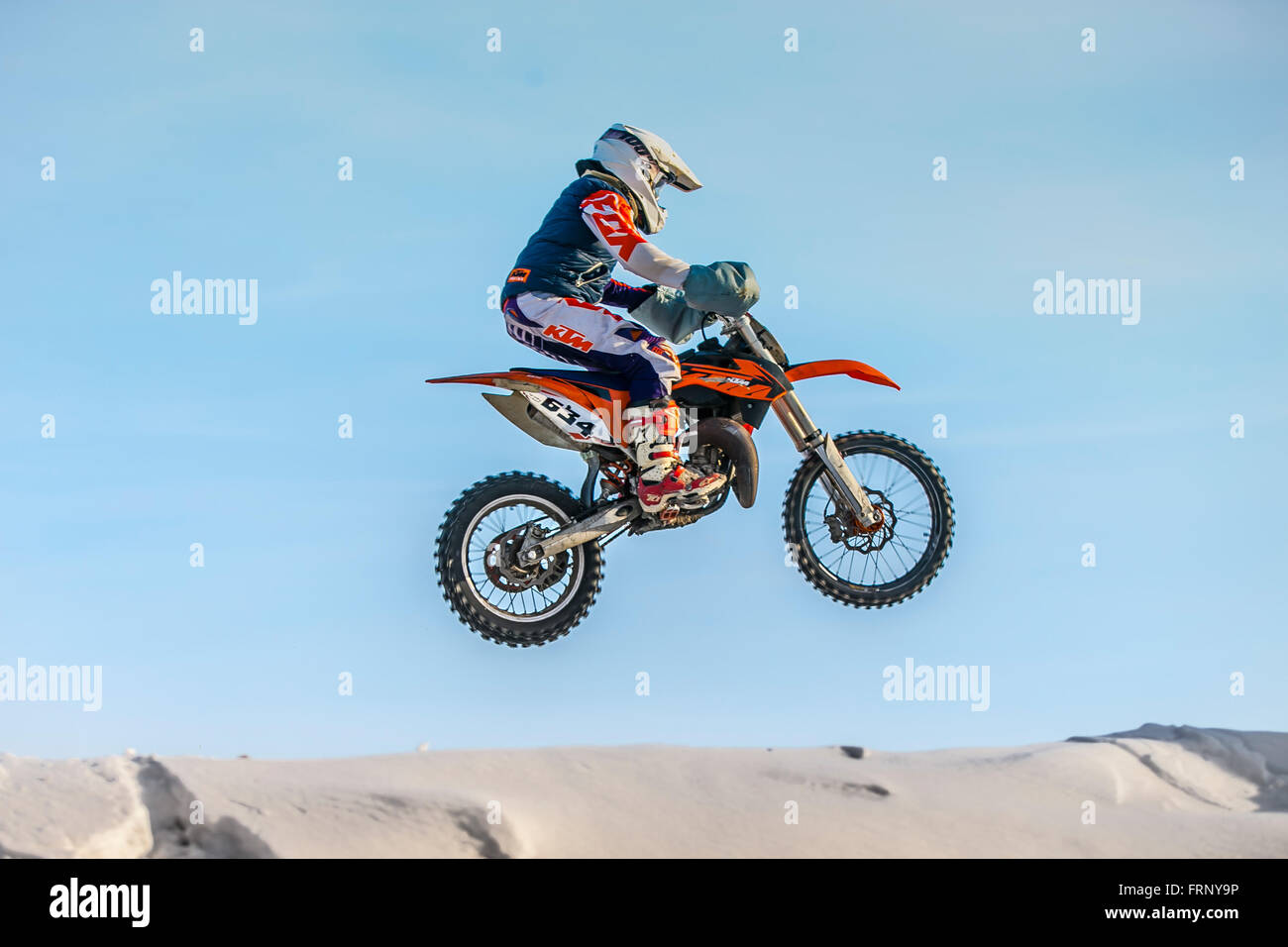 Moto Racer haut vol sur fond de ciel bleu au cours de l'hiver la Coupe du motocross Banque D'Images