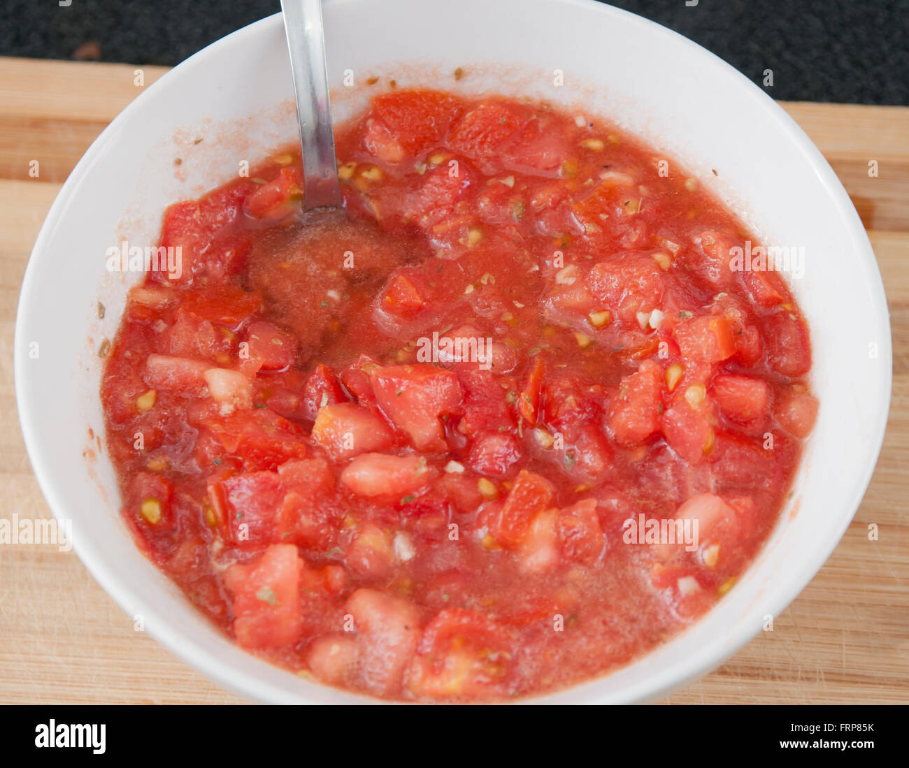 Couper la tomate avec l'huile, le sel, l'origan et l'ail. Banque D'Images