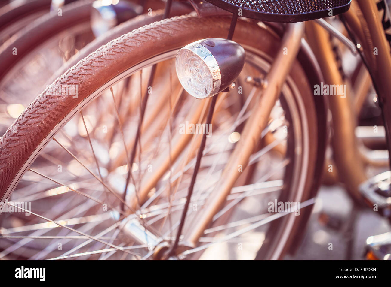 Close Up de la roue de bicyclette sur le stationnement en ville européenne. Soleil Soleil à travers les rayons de la roue. Close Up de phare de vélo Banque D'Images