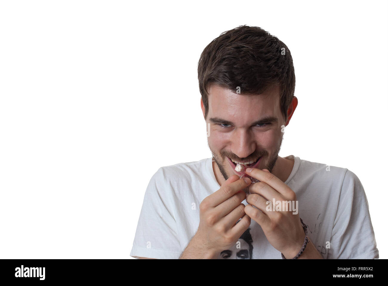 Young man putting un bonbon dans sa bouche avec un regard diabolique