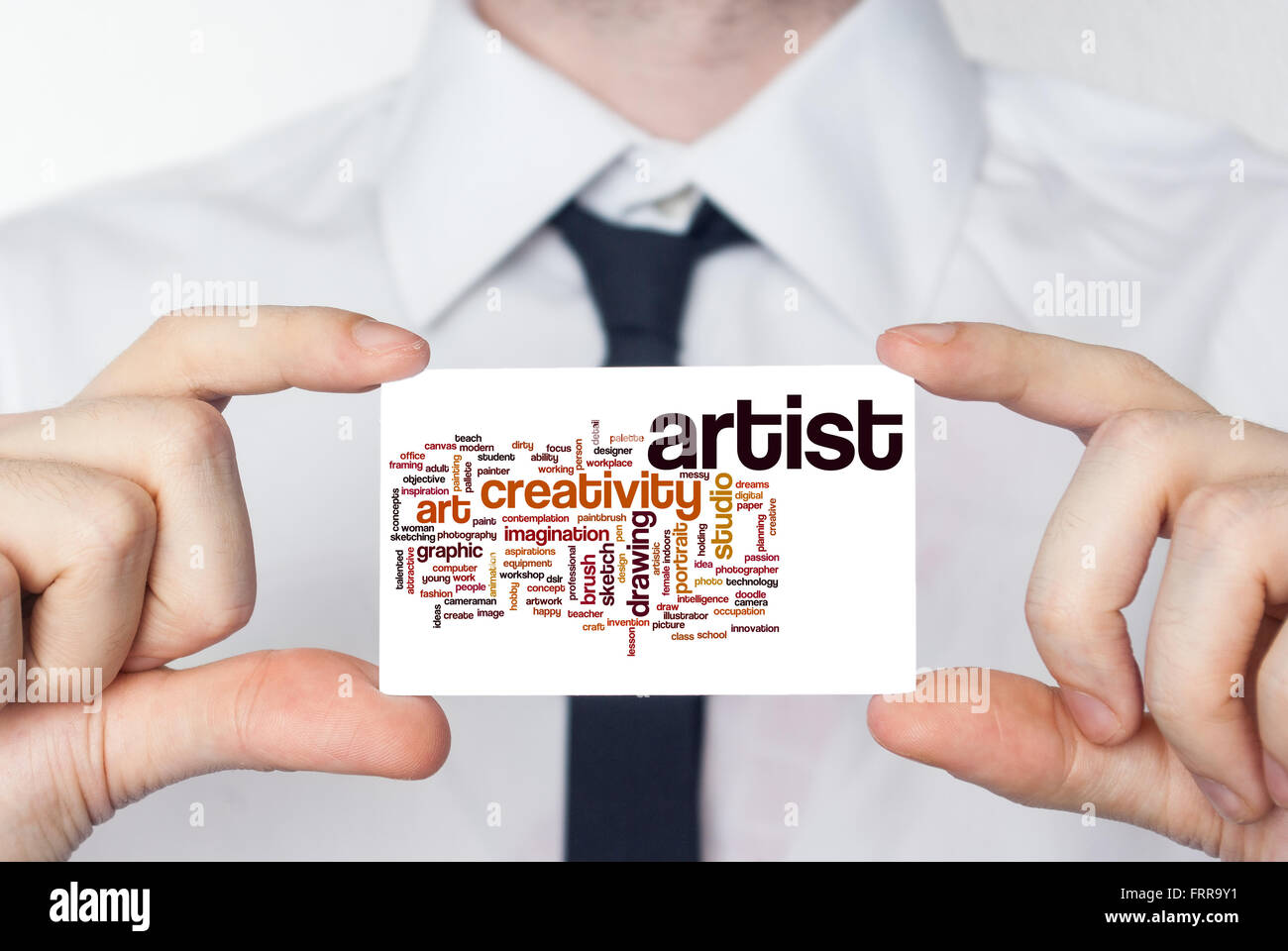 Artiste. Businessman en chemise blanche avec une cravate noire montrant ou holding business card Banque D'Images