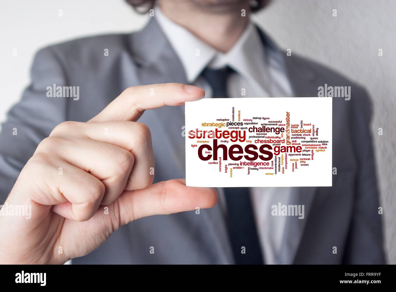 Les échecs. Homme d'affaires en costume avec une cravate noire montrant ou holding business card Banque D'Images