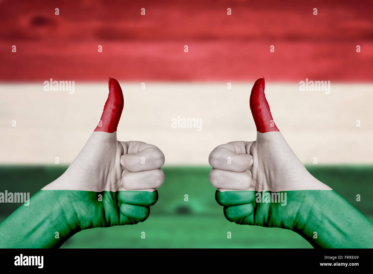 Hongrie drapeau peint sur female hands up floue avec fond de bois Banque D'Images