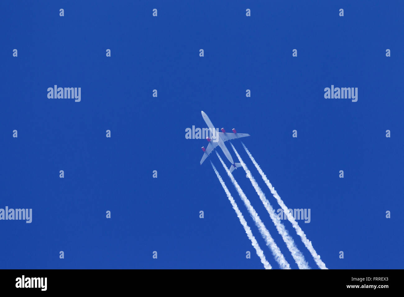 Les traînées d'échappement du moteur - cirrus aviaticus - formant derrière quatre-moteur à l'Airbus A340 avion contre le ciel bleu Banque D'Images