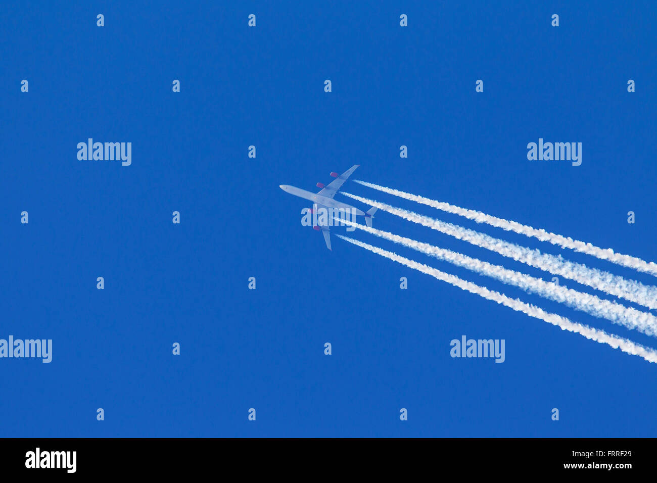 Les traînées d'échappement du moteur - cirrus aviaticus - formant derrière quatre-moteur à l'Airbus A340 avion contre le ciel bleu Banque D'Images