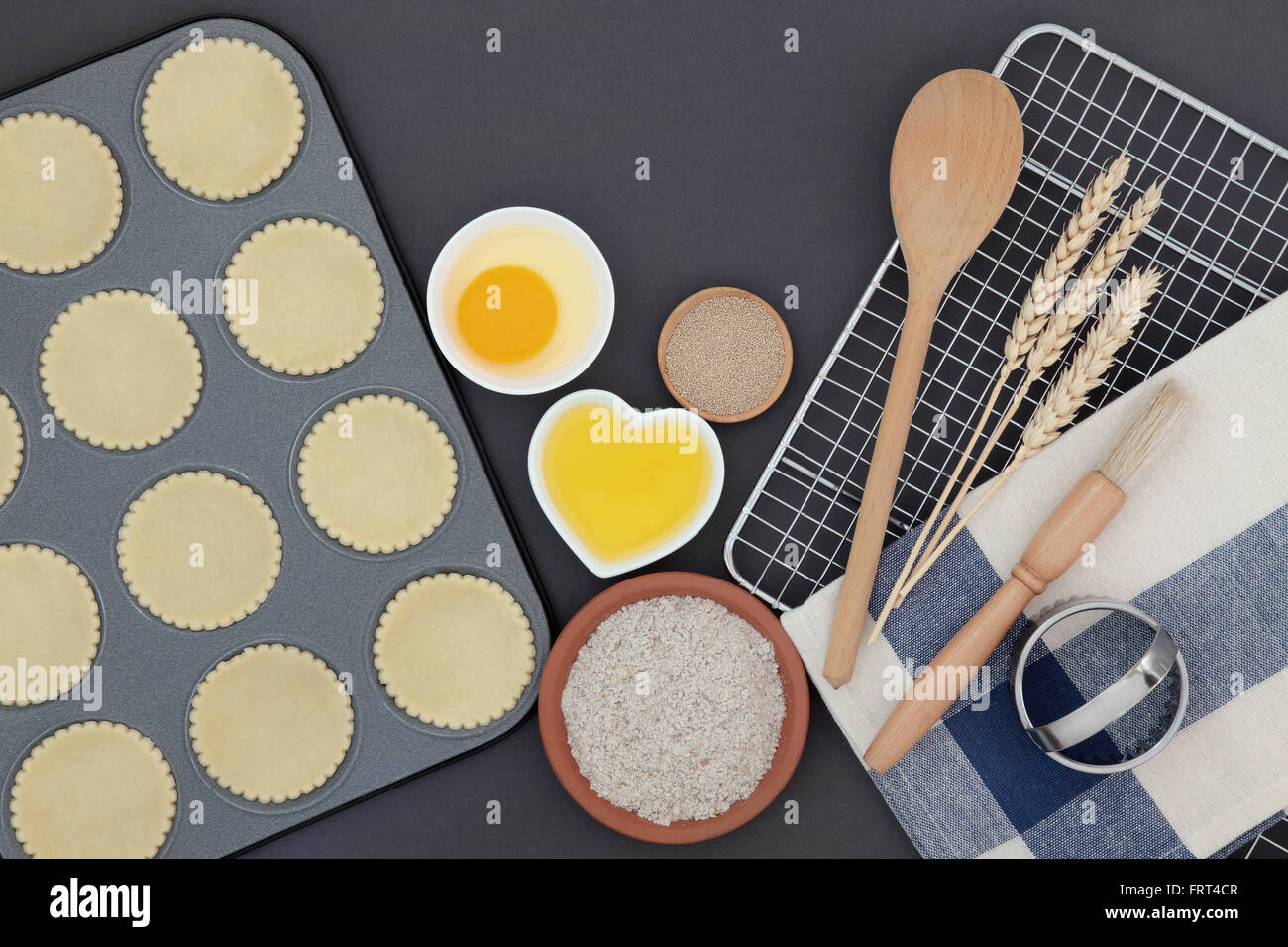 Des formes en pâte de cuisson avec ingrédients et ustensiles sur fond gris. Banque D'Images