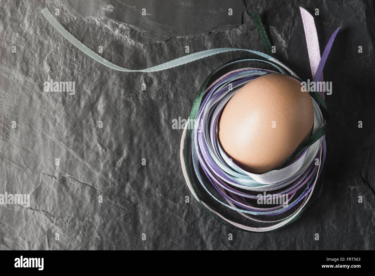Egg avec des rubans colorés sur la table en pierre Vue de dessus Banque D'Images