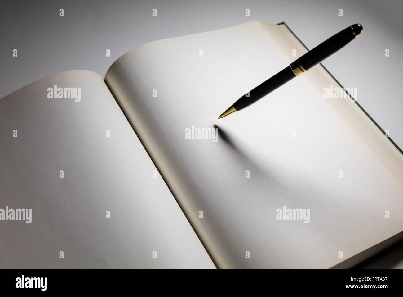 Pages blanches d'un livre ouvert avec un stylo Banque D'Images