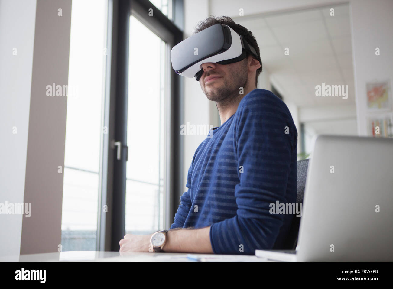 Smiling homme portant des lunettes de réalité virtuelle dans le bureau Banque D'Images