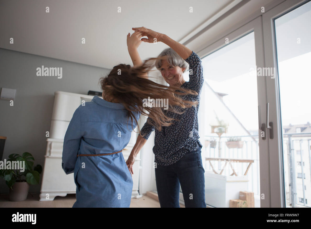 Petite fille danse avec sa grand-mère à la maison Banque D'Images
