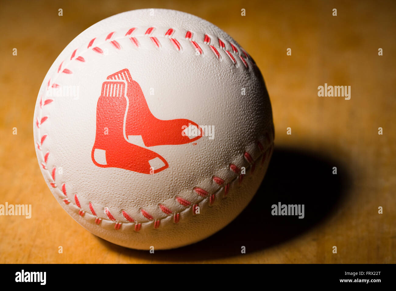 Baseball en caoutchouc blanc avec les Red Sox de Boston logo imprimé sur le côté avec surpiqûres rouges reposant sur une table en bois Banque D'Images
