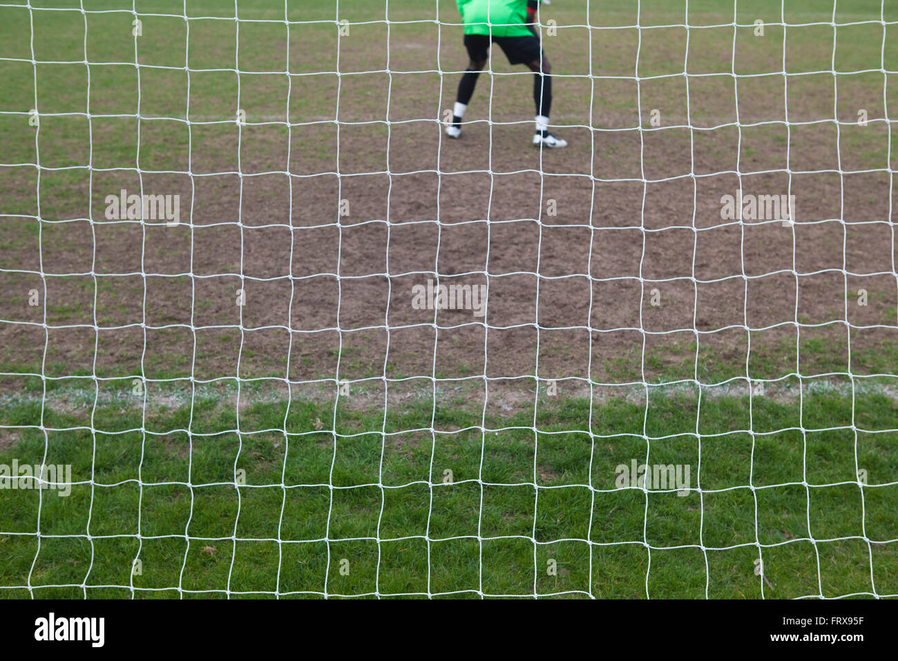 Un match de football de la ville locale et le gardien de but vu de derrière par la compensation de l'objectif se prépare à faire une sauvegarde dans le jeu. Banque D'Images