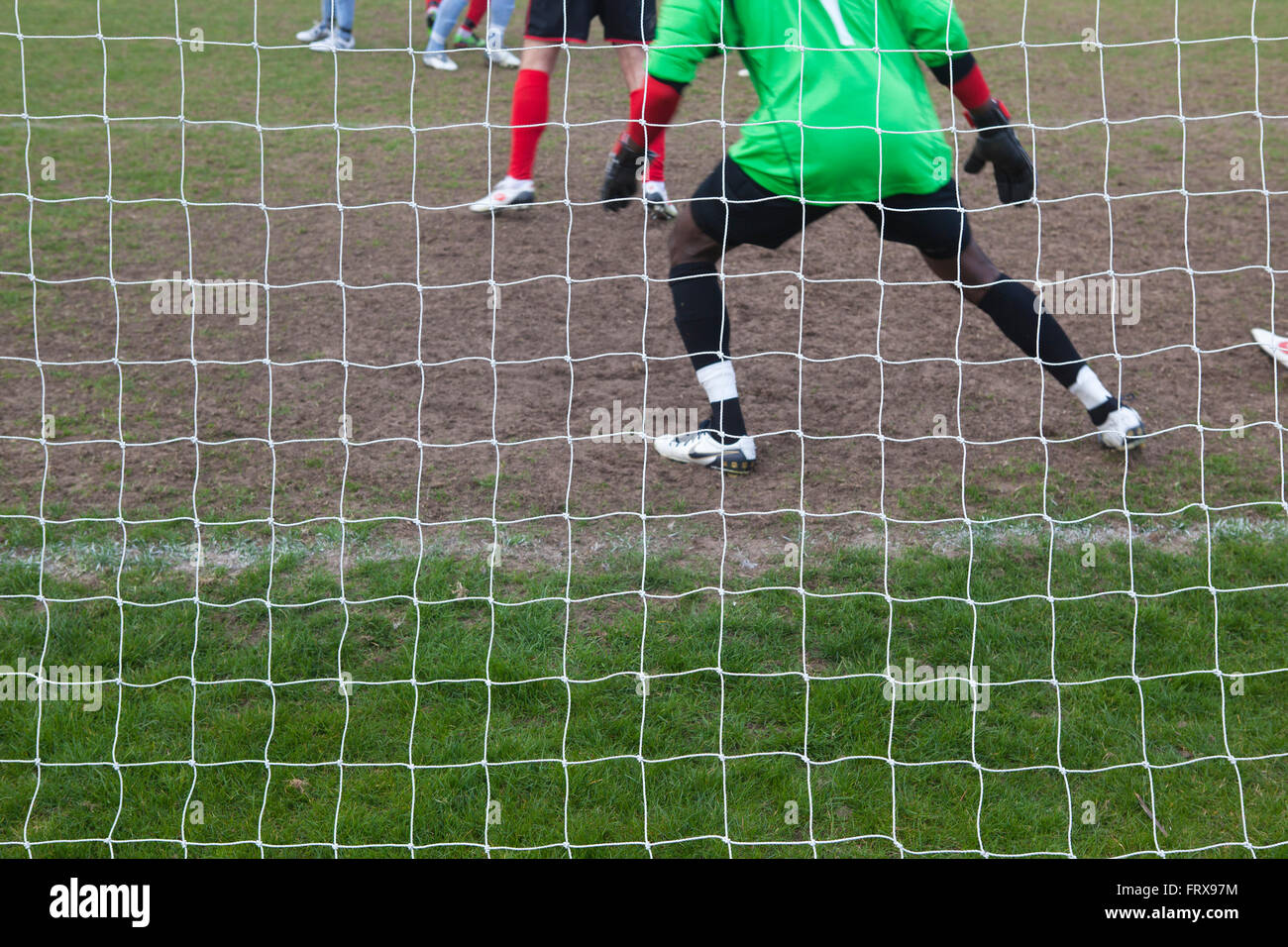 Un match de football de la ville locale et le gardien de but vu de derrière par la compensation de l'objectif se prépare à faire une sauvegarde dans le jeu. Banque D'Images