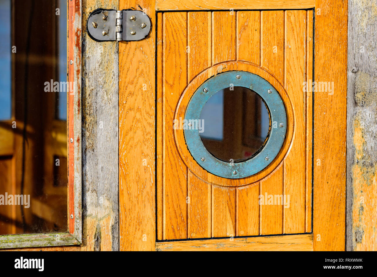 Détail d'une petite fenêtre circulaire sur un bateau en bois porte de la cabine. Une charnière et d'une plus grande partie visible de la fenêtre. Un cadre métallique surrou Banque D'Images Détail d'une petite fenêtre circulaire sur un bateau en bois porte de la cabine. Une charnière et d'une plus grande partie visible de la fenêtre. Un cadre métallique surrou Banque D'Images