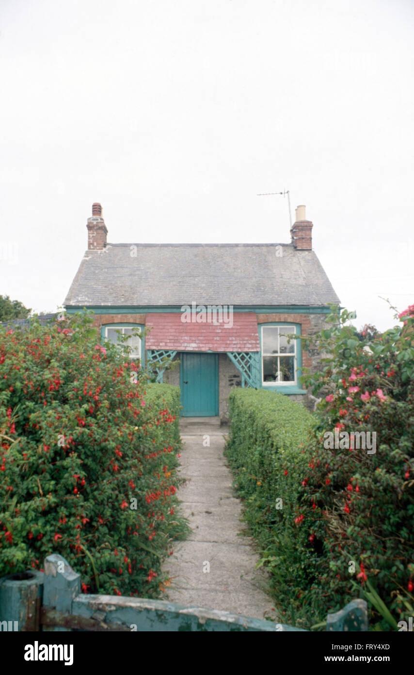 Chemin dans le jardin avant longtemps de la petite maison en brique avec une porte verte Banque D'Images