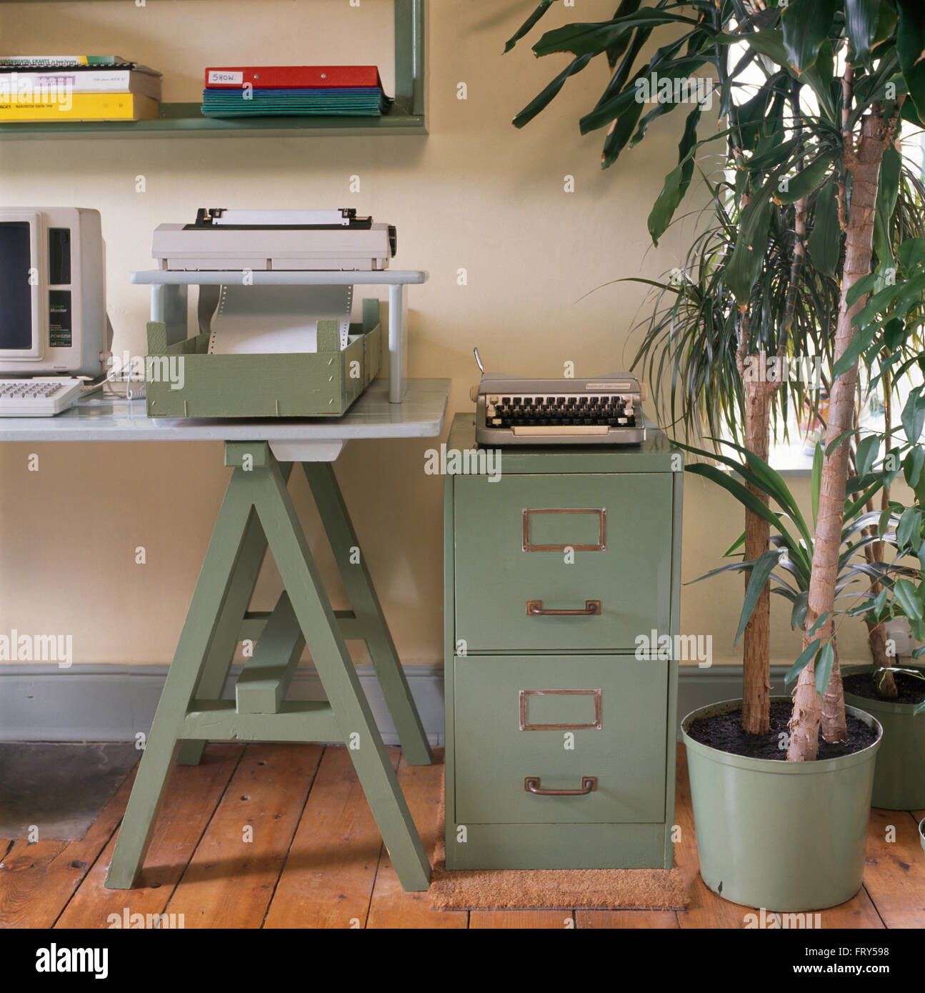 Machine à écrire portable Vintage turquoise sur classeur à côté d'usine à 90 ans home office avec une imprimante sur table tréteau Banque D'Images