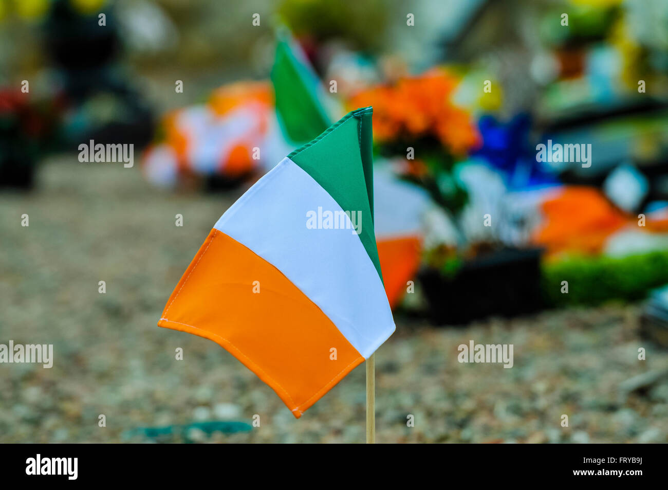 Drapeaux tricolores irlandais et fleurs laissés sur un terrain d'enterrement républicain irlandais à Belfast Banque D'Images