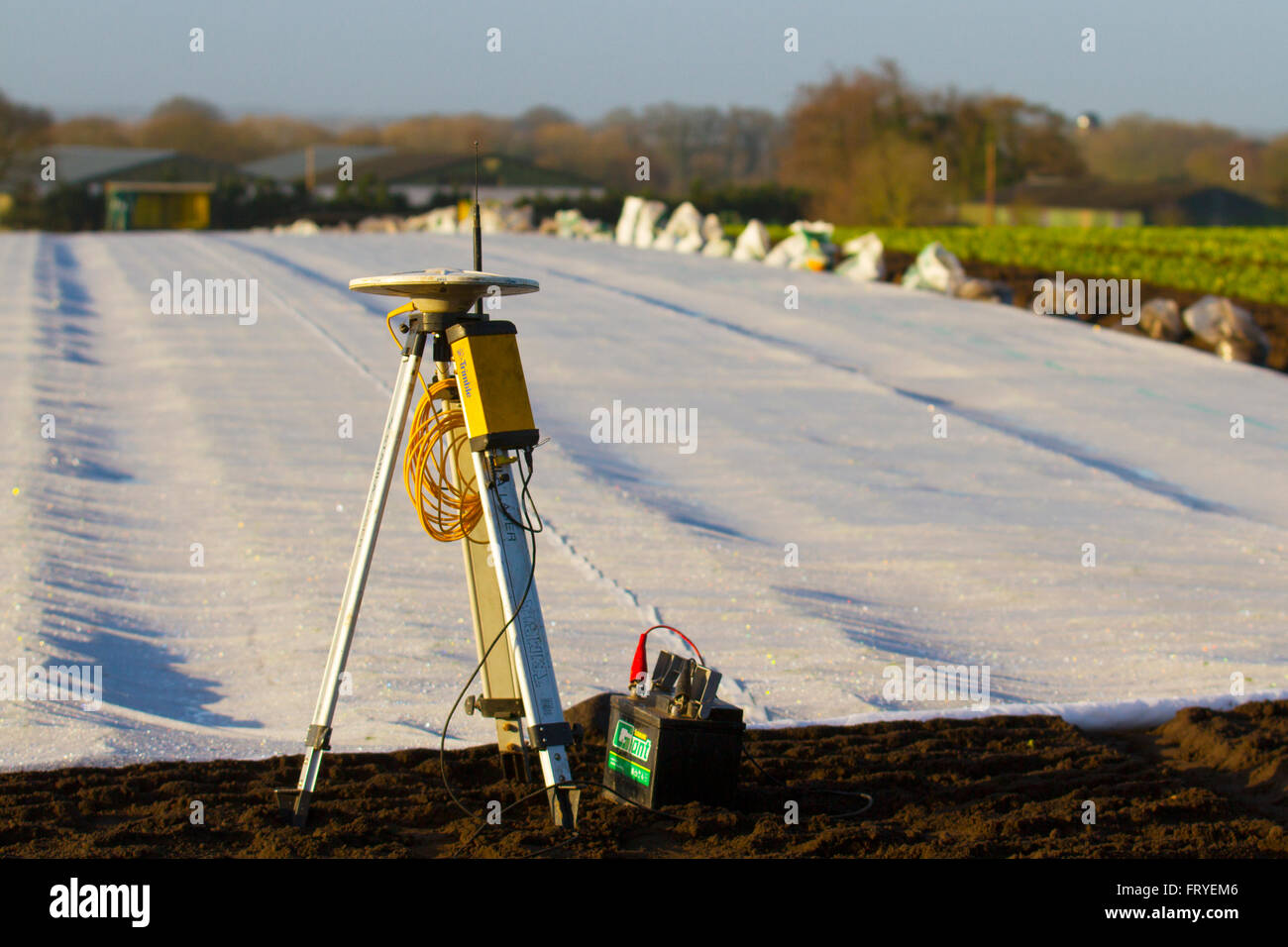 Récepteur GPS externe utilisé en Burscough, Lancashire, UK 25 Mars, 2016. Météo britannique. Un paysage se couvrir de molleton blanc comme les agriculteurs utilisent le guidage par satellites GPS Trimble tracteur matériel systèmes pour tracer leurs champs et cette plante saisons' plants de laitue. L'horticulture est une fine toison, polypropylène non tissé, tissu qui est utilisé comme paillis flottants pour protéger tôt et tard les cultures et d'autres plantes délicates contre le froid et le gel, ainsi que les insectes nuisibles au cours de la saison de croissance normale. Banque D'Images