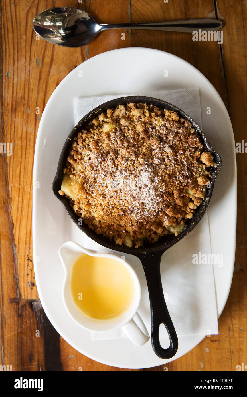 Crumble aux pommes servi avec un pot de crème anglaise à Londres, en Angleterre. Banque D'Images