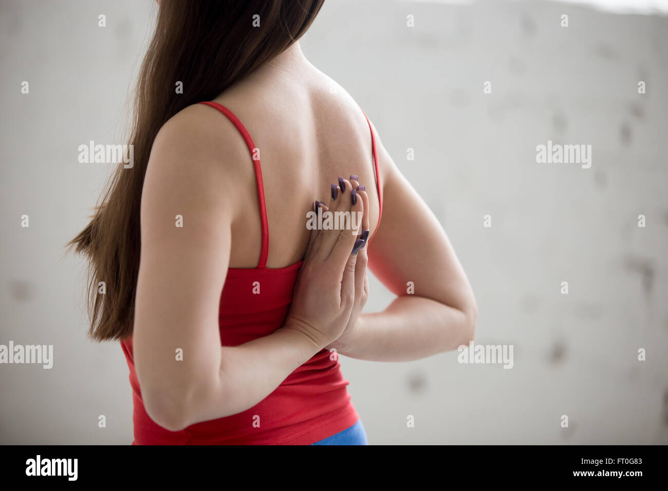 Belle jeune femme dans des vêtements colorés à l'intérieur de l'intérieur de style loft. Girl holding Anjali Mudra derrière Banque D'Images