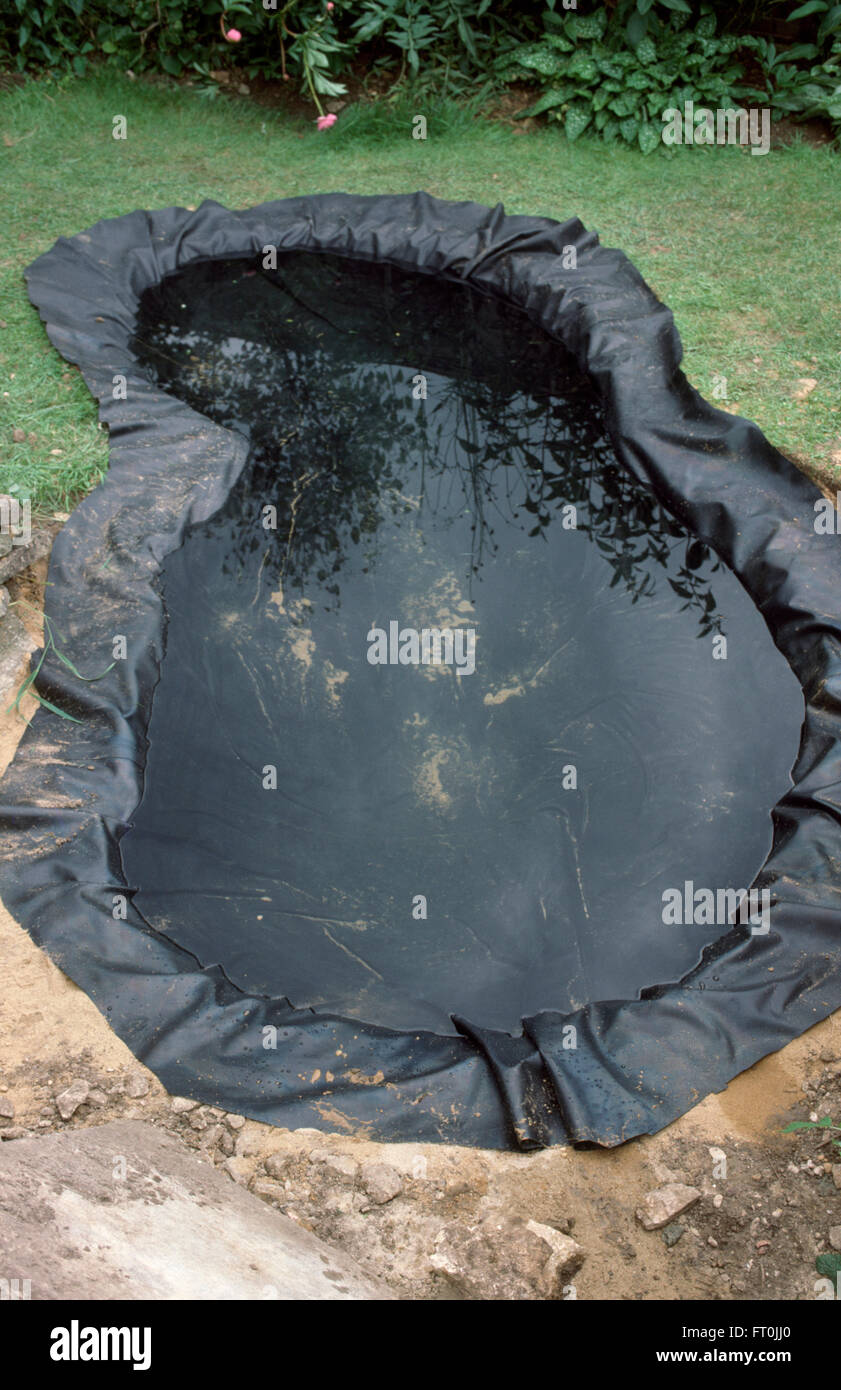 Vue d'un nouvel étang bordé d'un plastique noir et rempli d'eau Banque D'Images