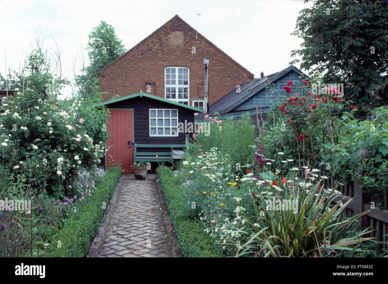 Brique Herringbone chemin pavé entre les frontières avec chevrons avec fort menant au hangar en bois de jardin d'un chalet Banque D'Images