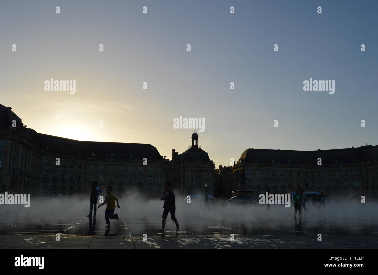 Enfants jouant dans le jet du miroir d'eau à Bordeaux, France en début de soirée Banque D'Images