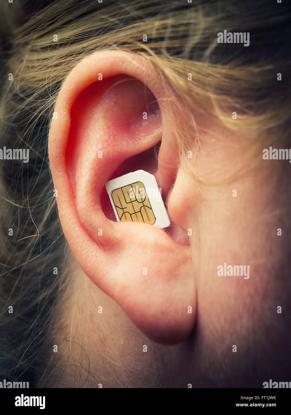 Carte SIM mobile dans l'oreille comme un symbole de la communication moderne. Banque D'Images