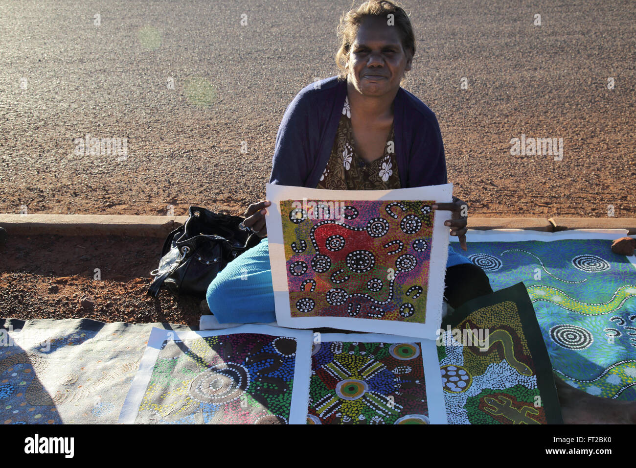 Un artiste aborigène jean brumby afficher ses peintures à Uluru dans le centre rouge de l'Australie Banque D'Images