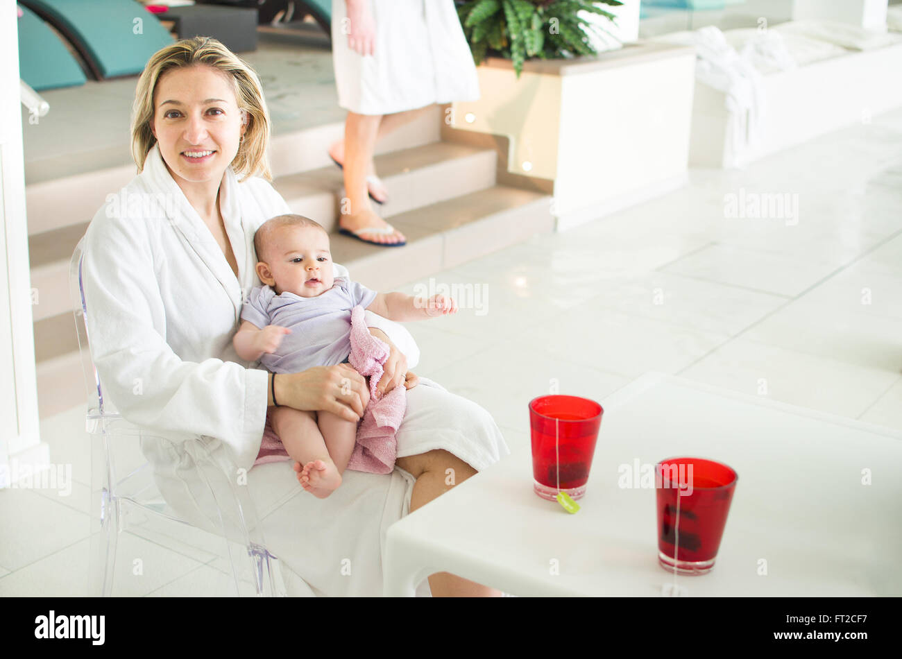 Maman dans un spa avec nouveau-né blanc peignoir boire tisane Banque D'Images