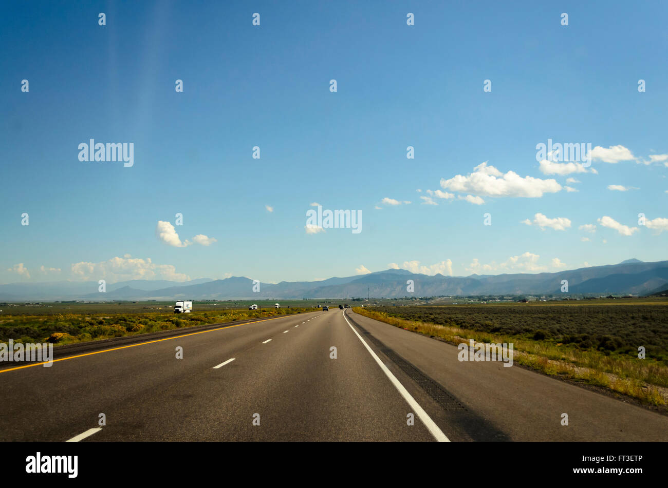 La route ouverte sous ciel bleu avec des nuages blancs moelleux. Banque D'Images