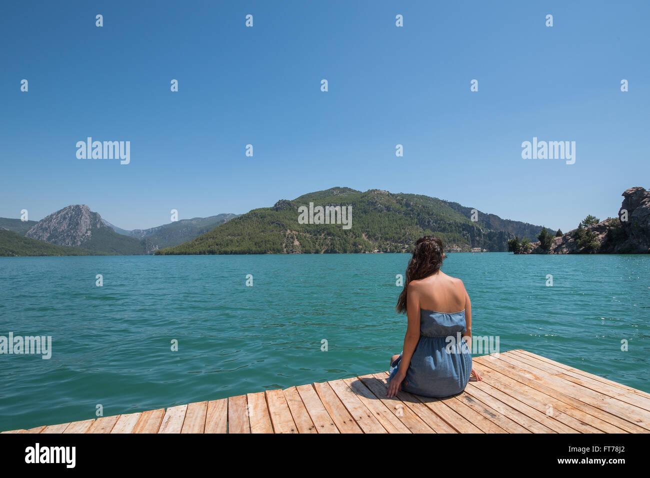 Young woman sitting on pier et profitez de la vue sur le lac Banque D'Images