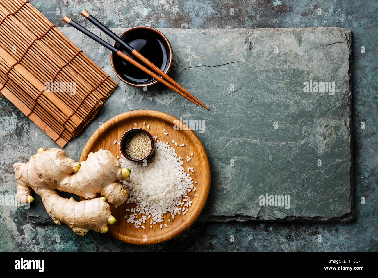 Riz blanc brut, le gingembre, la sauce soja et de sushi baguettes sur fond ardoise gris Banque D'Images