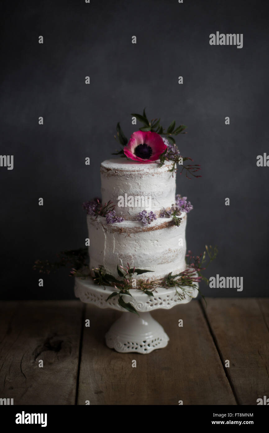 Gâteau fait maison, décorée de fleurs, sur un stand. Fond sombre. Banque D'Images