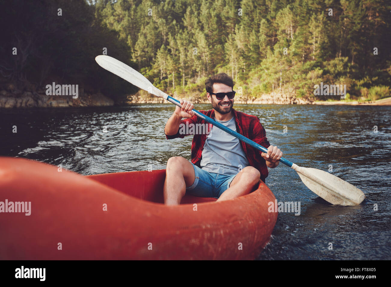 Jeune homme kayak sur un lac. Heureux jeune homme canoë dans un lac. Banque D'Images
