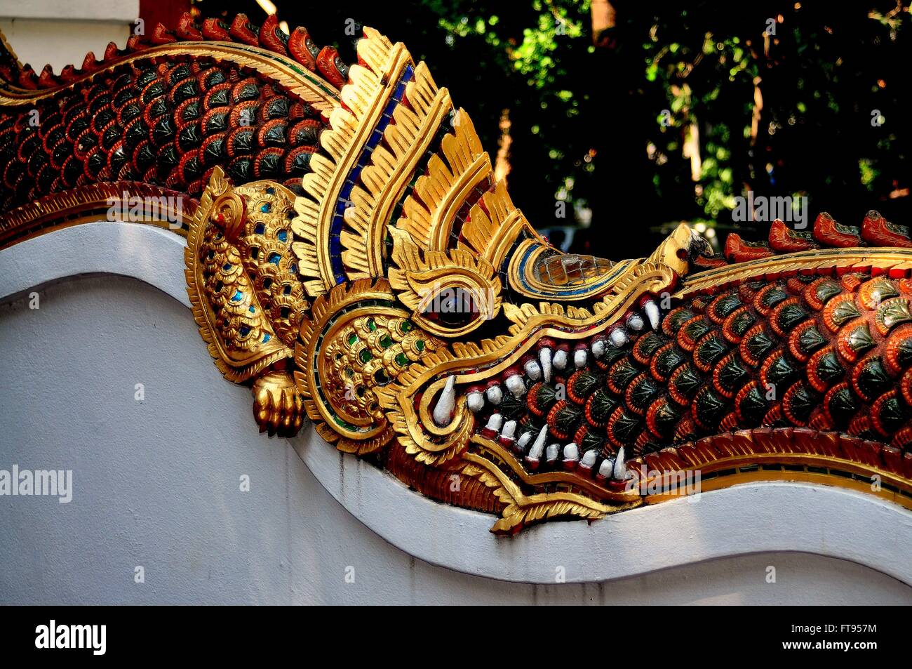 Chiang Mai, Thaïlande : dragon doré avec dents féroces enroulée autour de la queue d'un autre dragon scaley sur Wat Ku Tao Banque D'Images